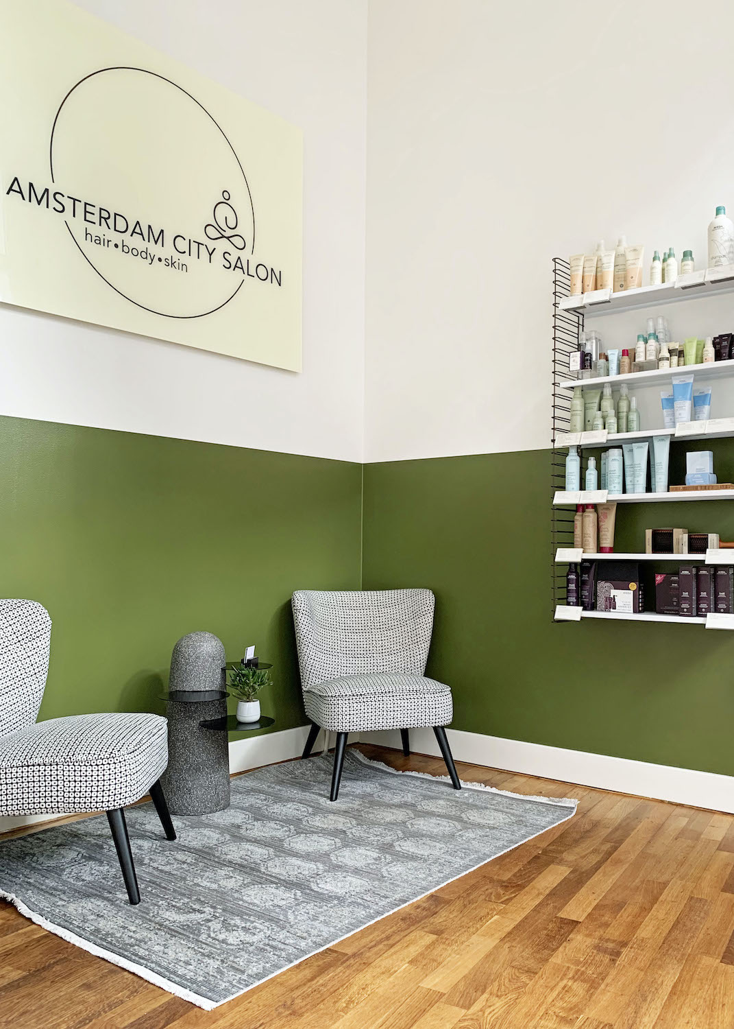 De ontvangstruimte van Amsterdam City Salon met groene wanden en natuurlijke producten